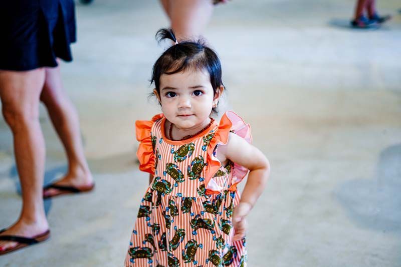 A little girl in a dress is standing in front of a group of people.