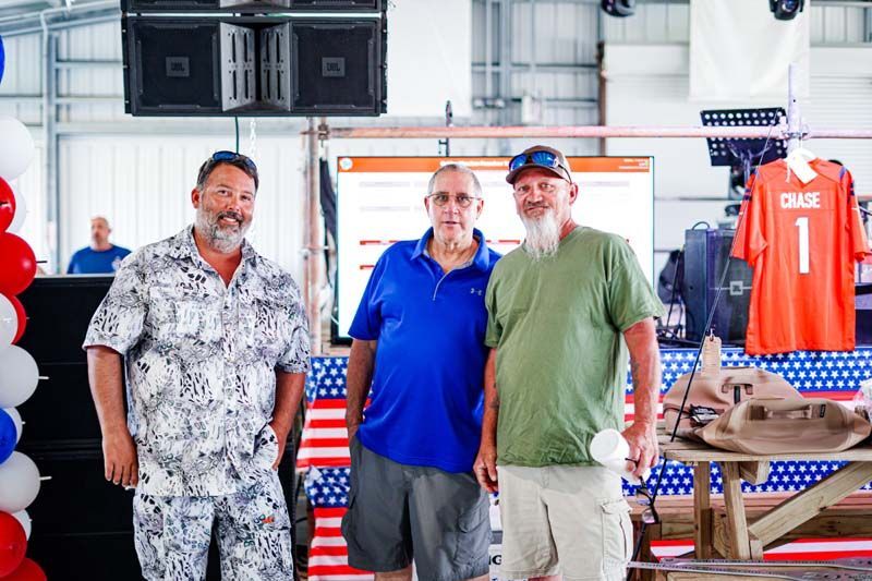 Three men are standing next to each other in a room.