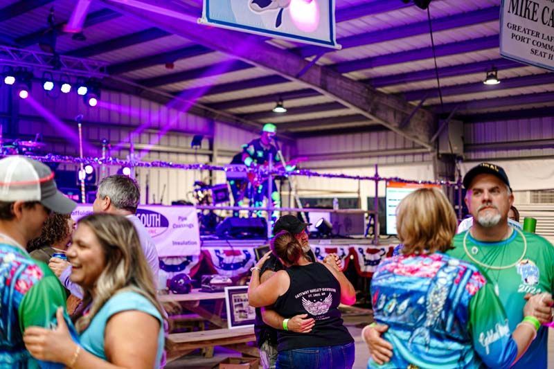 A group of people are dancing in a room with purple lights.