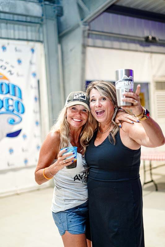Two women are standing next to each other holding bottles of beer.