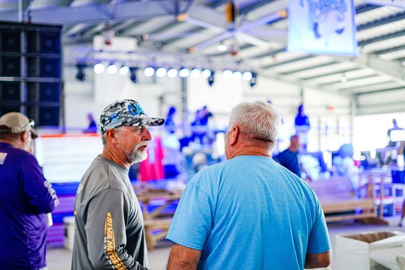 Two men are standing next to each other in a room and talking.