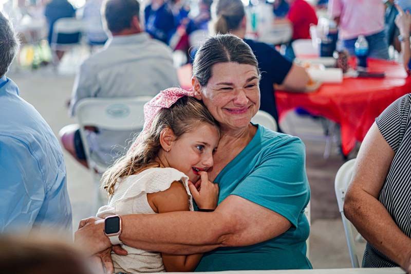 A woman is holding a little girl in her arms at a party.