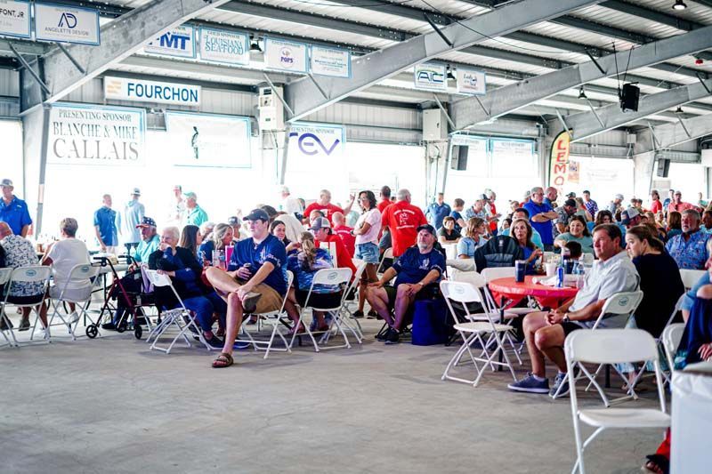 A large group of people are sitting in chairs under a roof.