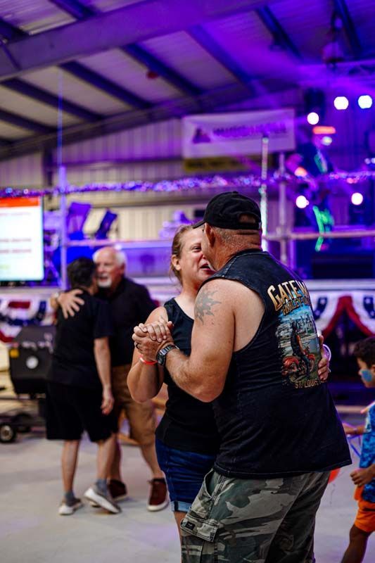 A group of people are dancing in a room with purple lights.