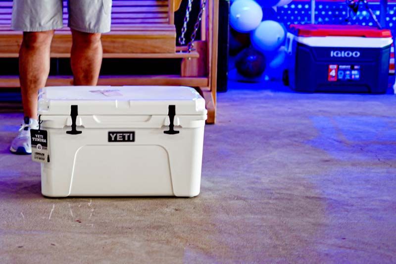 A man is standing next to a white yeti cooler.