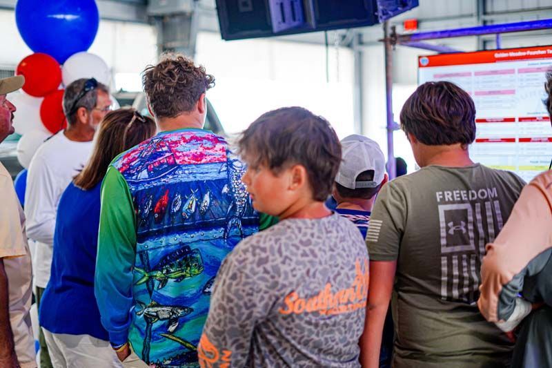 A group of people are standing in a line looking at a screen.