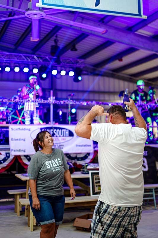 A man is taking a picture of a woman dancing at a concert.
