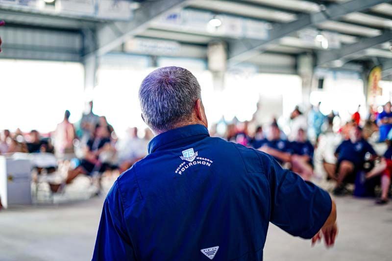 A man in a blue shirt is standing in front of a crowd of people.