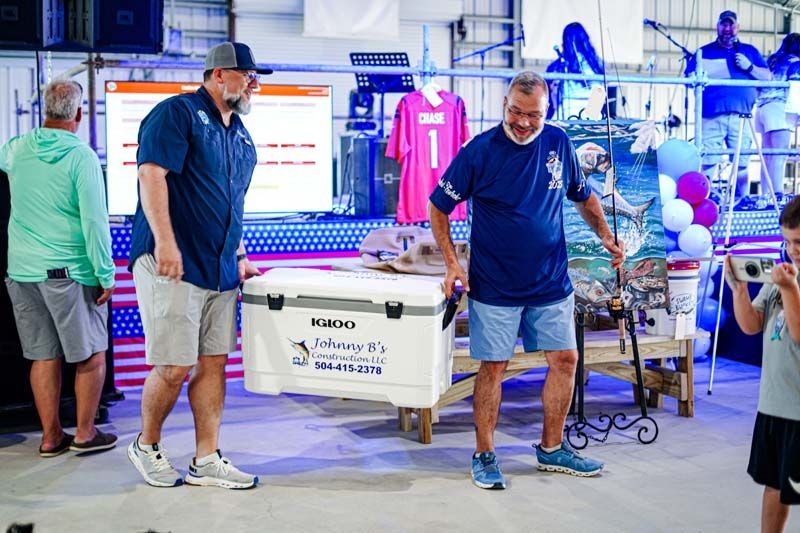 Two men are carrying a large cooler in a store.