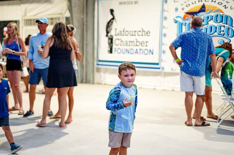A young boy is standing in front of a sign that says lafourche chamber foundation.