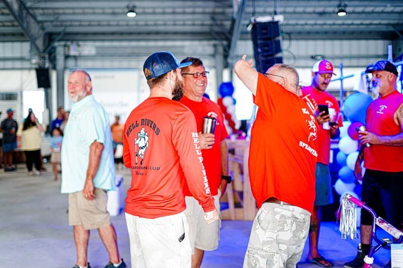A group of men are standing in a room talking to each other.