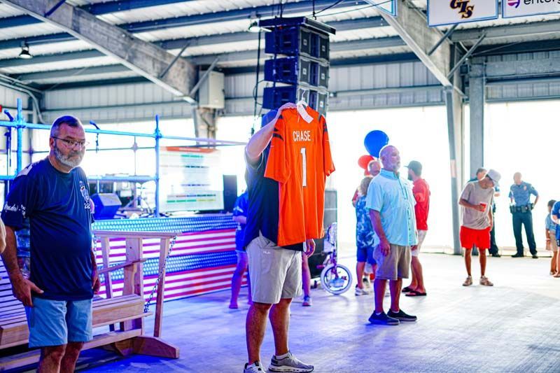A man is holding an orange jersey over his head.