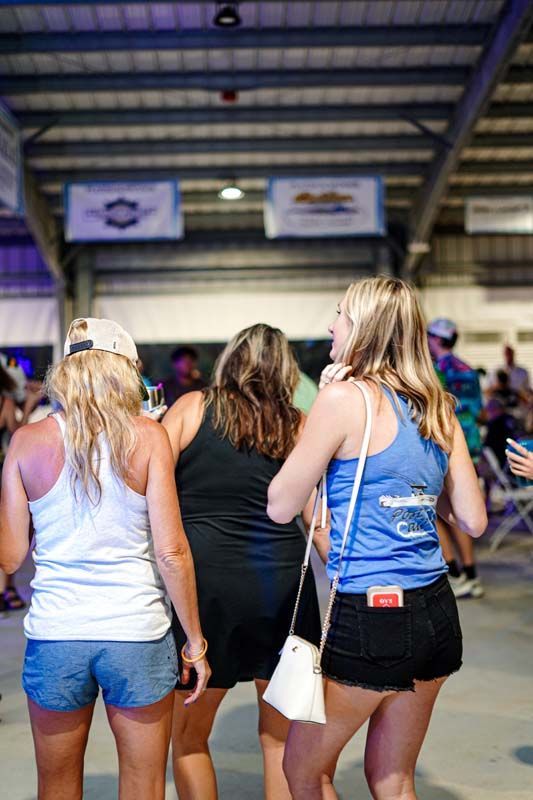 Three women are standing next to each other in a room.