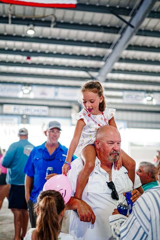 A man is carrying a little girl on his shoulders.