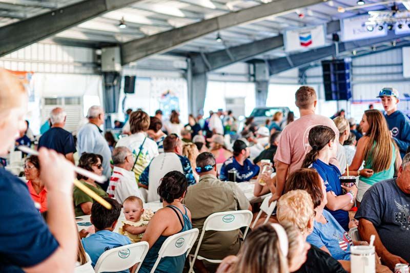 A large group of people are sitting at tables in a large room.