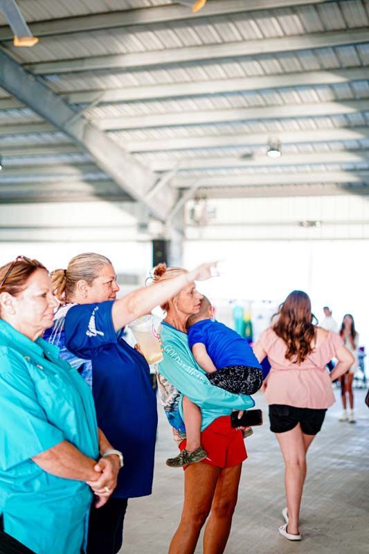 A woman is holding a child in a sling and pointing at something.