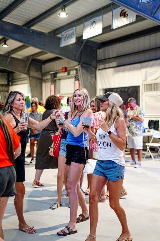 A group of women are standing in a room holding drinks.