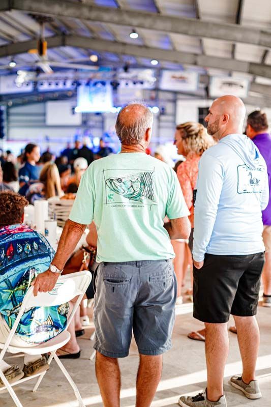 A group of men are standing in a room talking to each other.