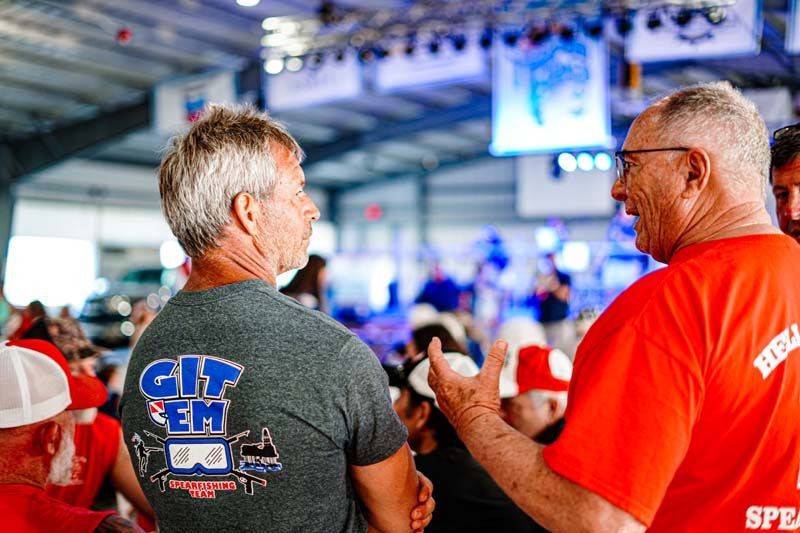 Two men in red shirts are talking to each other in a crowd.