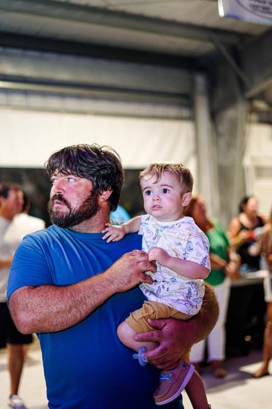 A man is holding a baby in his arms at a party.