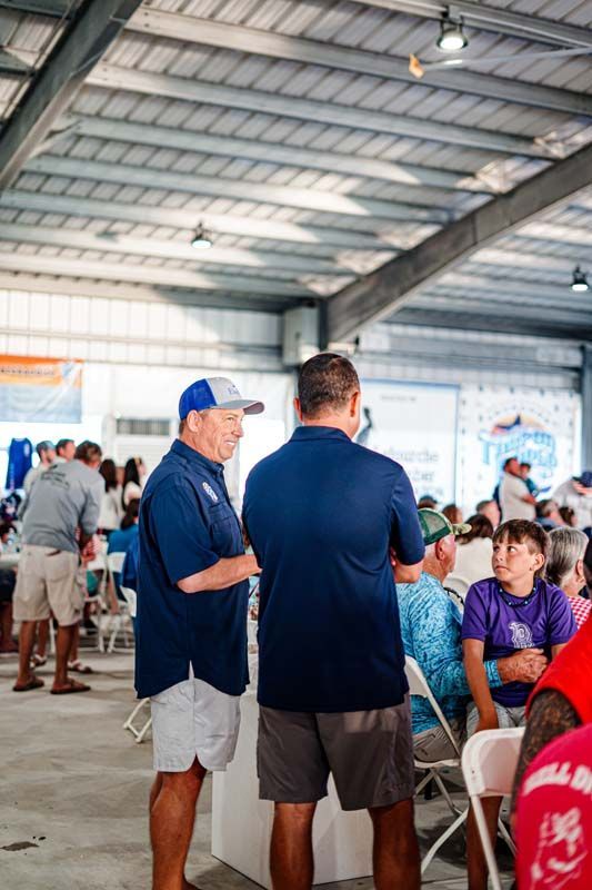 A group of men are standing in a room talking to each other.