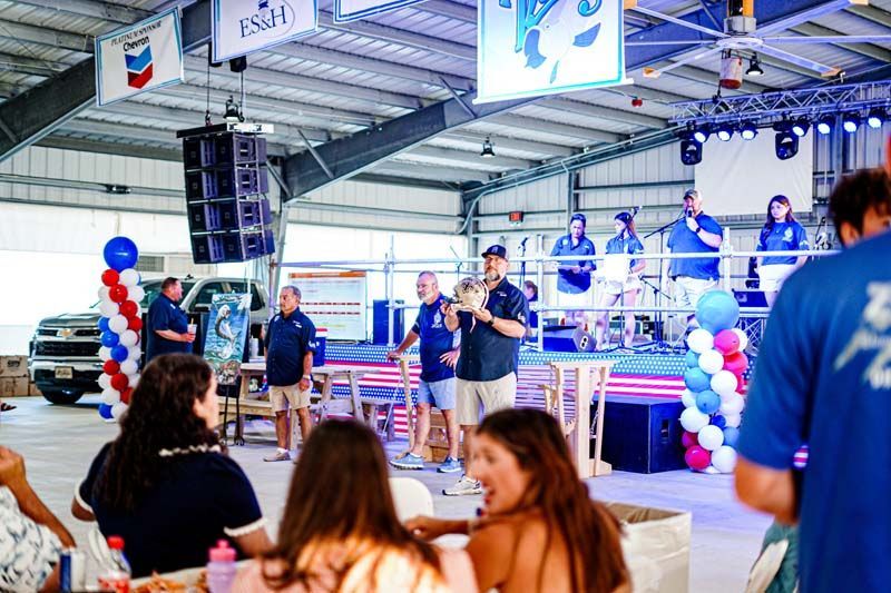 A group of people are sitting at tables in front of a stage at a concert.