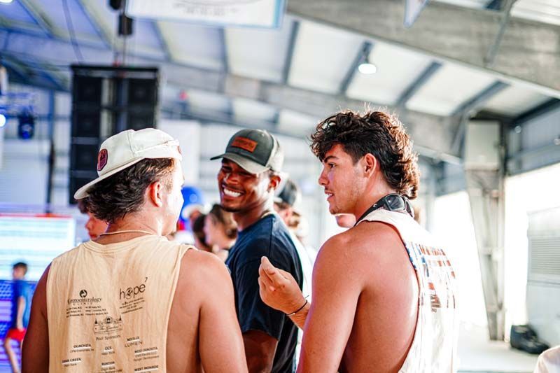 A group of young men are standing next to each other in a room and talking.