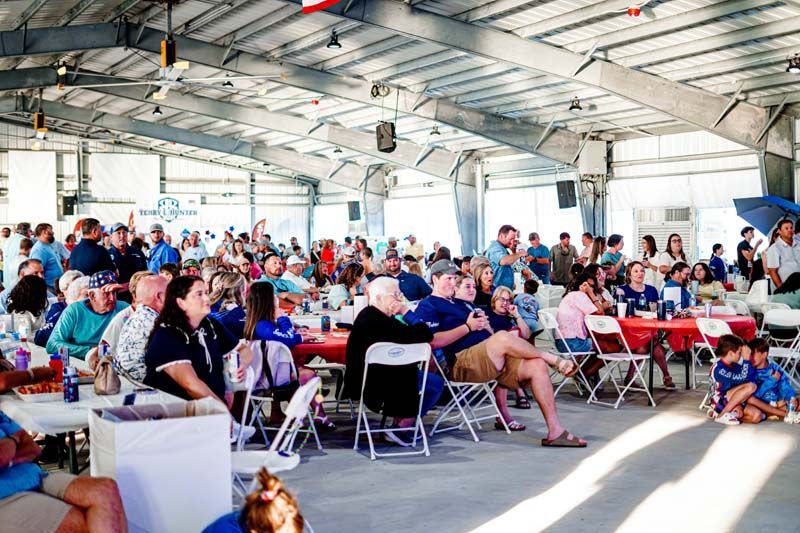 A large group of people are sitting at tables and chairs in a large room.