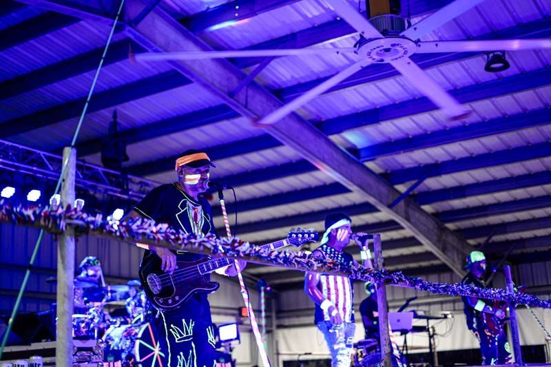 A man is playing a guitar and singing into a microphone on a stage.