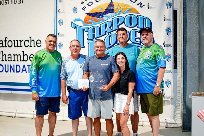 A group of people are posing for a picture in front of a tarpon lodge banner.