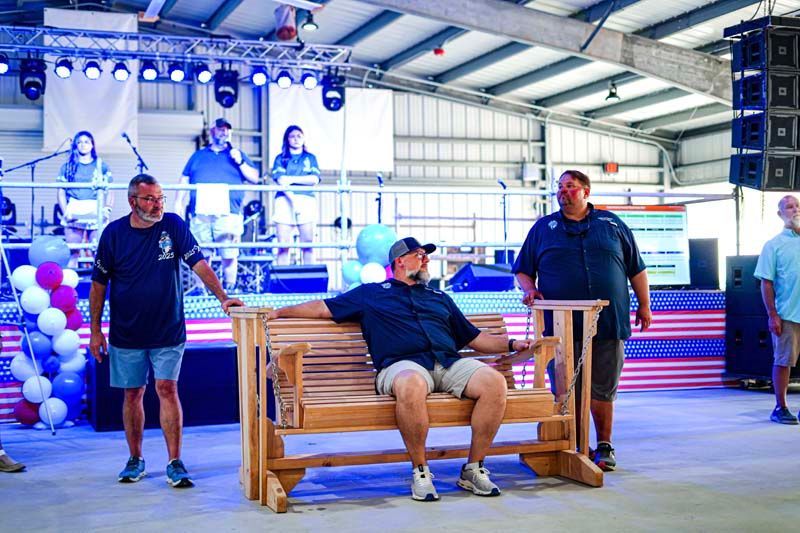 A group of men are standing around a wooden bench.
