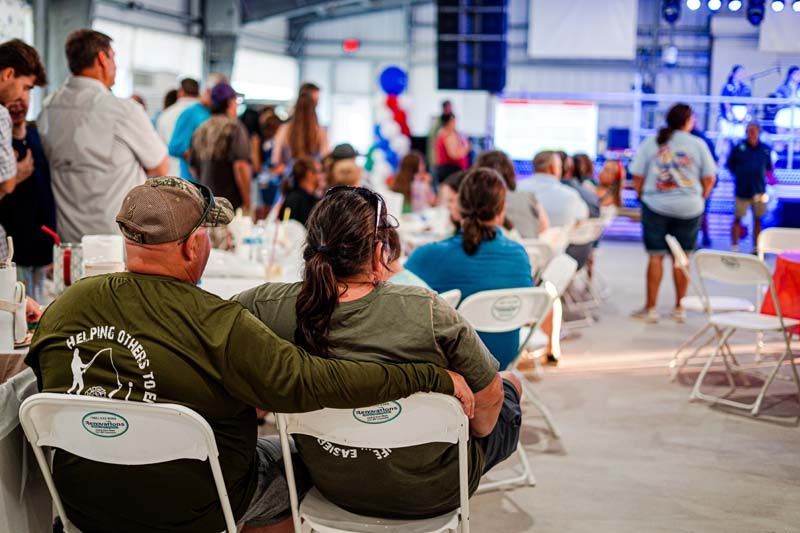 A man and a woman are sitting in chairs in front of a crowd.