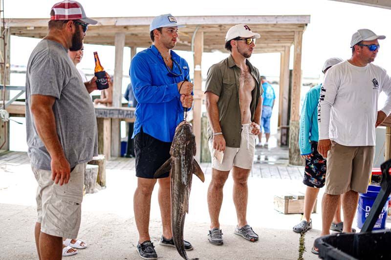 A group of men are standing next to each other holding fish.