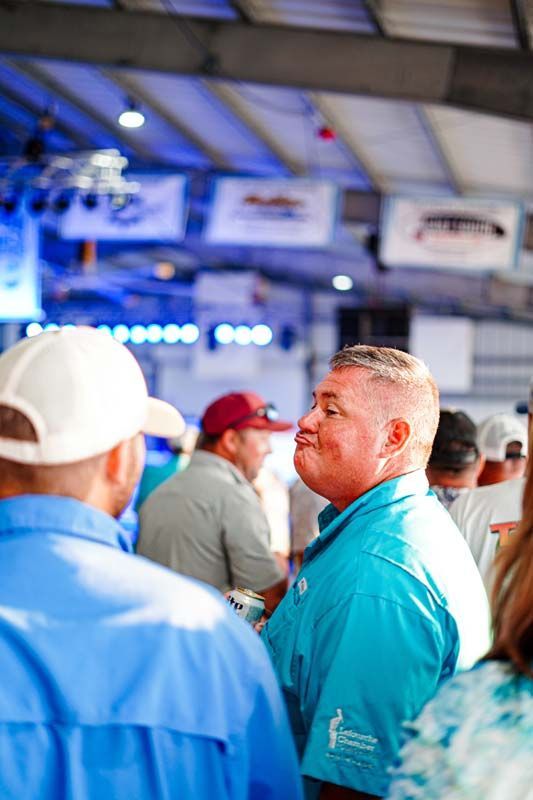 A man in a blue shirt is standing in a crowd of people.