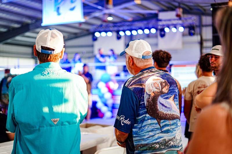 A group of people are standing in a room looking at a stage.