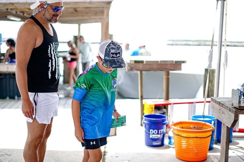 A man and a boy are standing next to each other on a beach.