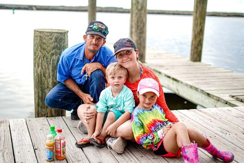 A family is posing for a picture on a dock.
