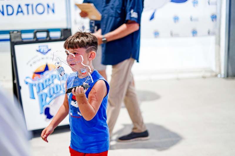 A young boy is standing in front of a sign that says foundation.