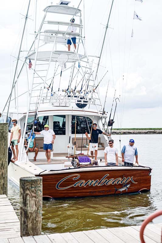 A large fishing boat is docked at a dock with people on it.