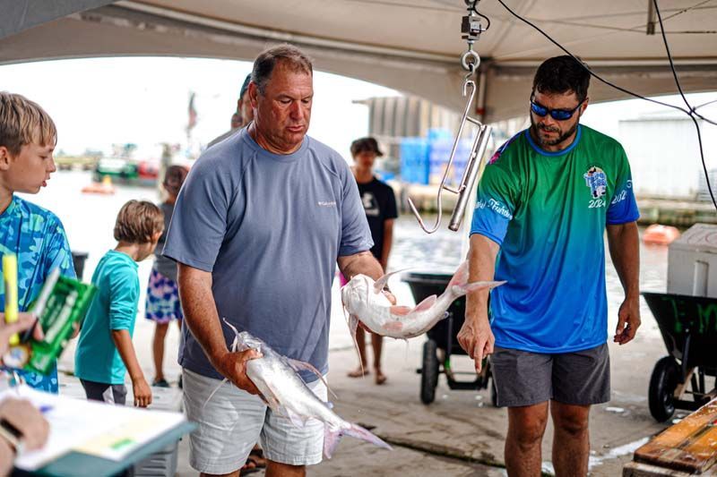 Two men are holding a large fish in their hands.