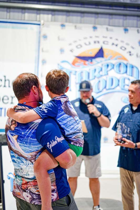 A man is holding a child in his arms in front of a sign.