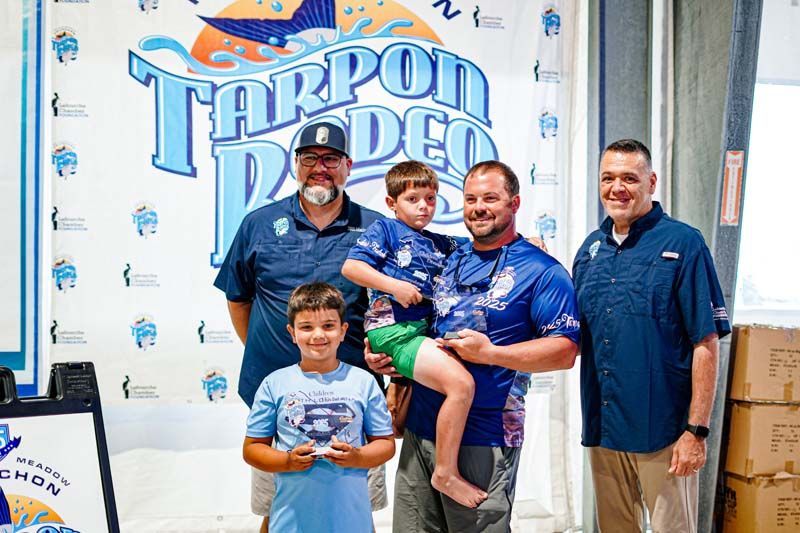 A group of men are standing next to each other in front of a sign that says tarpon rodeo.