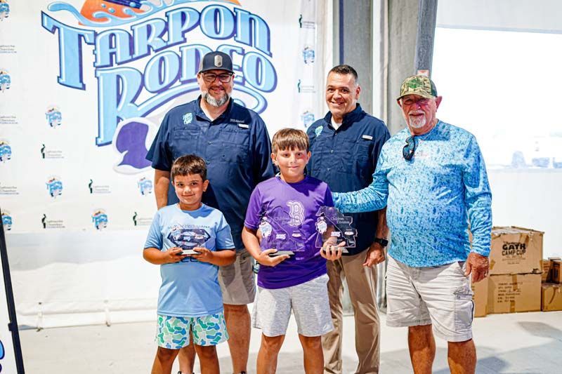 A group of men and two young boys are posing for a picture.