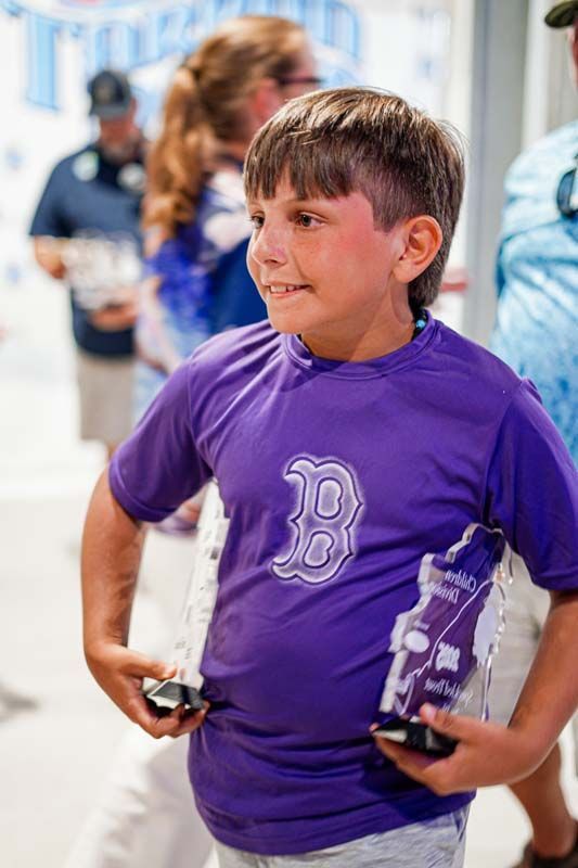 A young boy wearing a purple shirt is standing with his hands on his hips.
