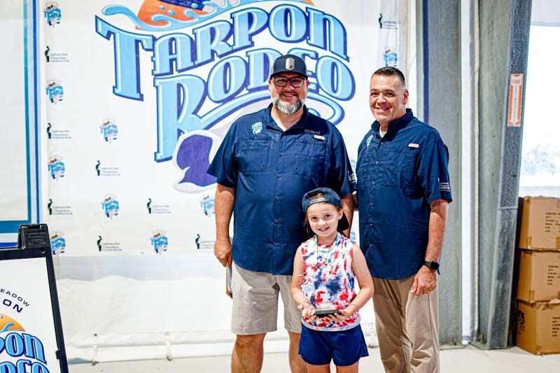 Three men and a little girl are standing in front of a tarpon pool sign.