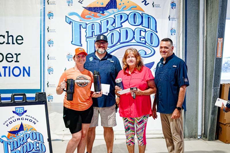 A group of people standing next to each other in front of a tarpon rodeo sign.