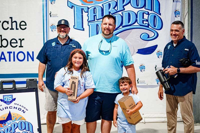 A group of people standing in front of a sign that says tarpon rodeo