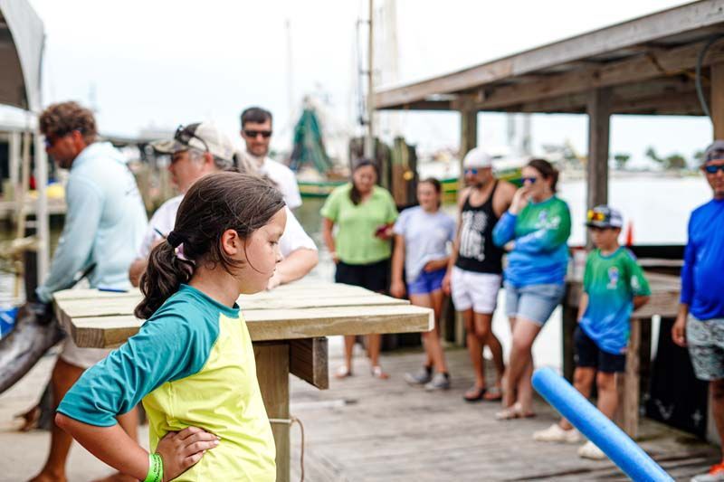 A group of people are standing around a table on a dock.