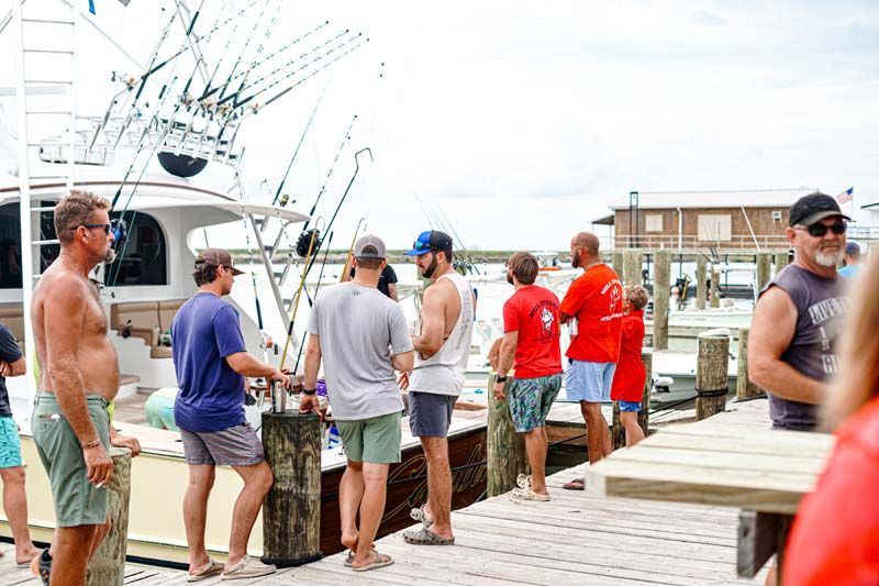 A group of men are standing on a dock next to a boat.