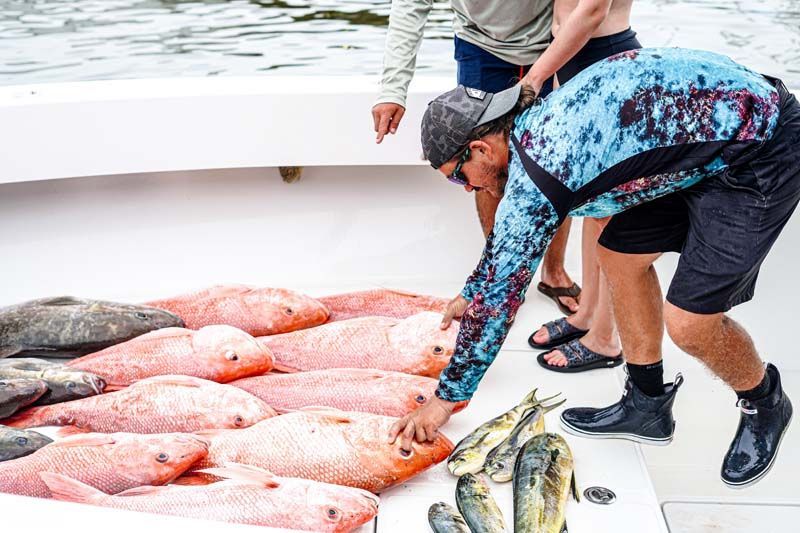 A man is reaching for a fish on a boat.